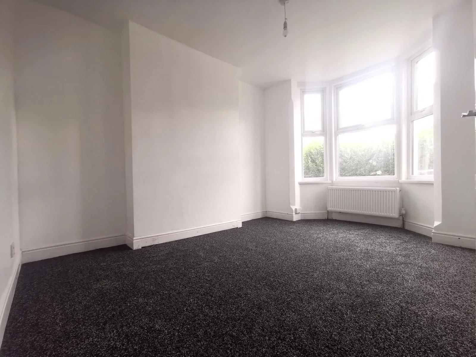 The same reception room after refurbishment, with the gas fire removed and a radiator fitted under the bay window