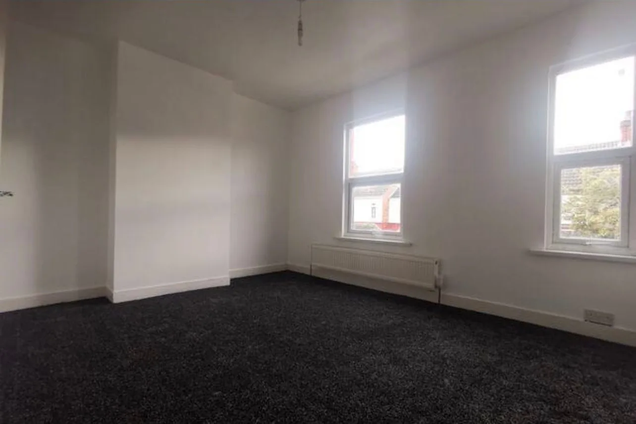 A finished bedroom with two windows and a radiator fitted against the wall on the new heating circuit