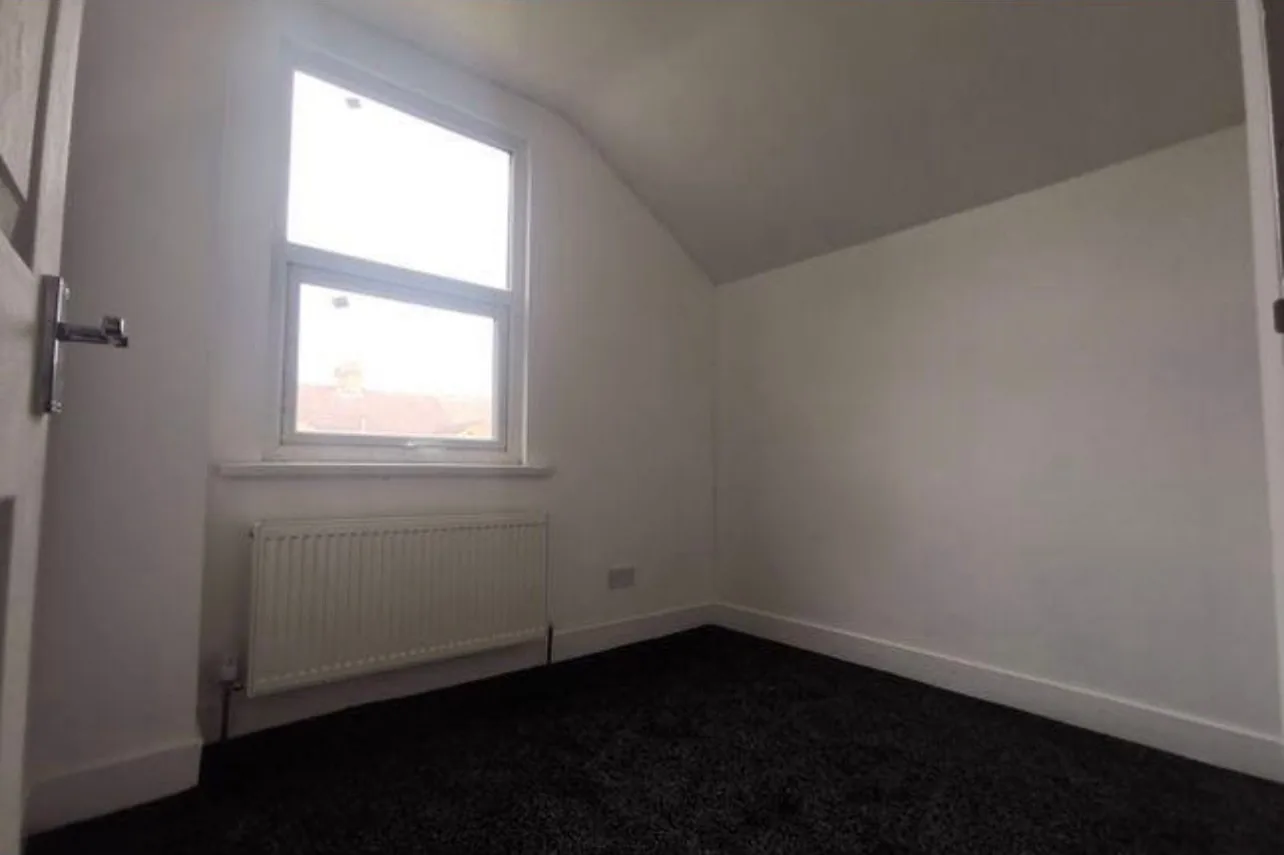 The new third bedroom under a sloped ceiling, with a radiator fitted below the window in the room that used to be the bathroom