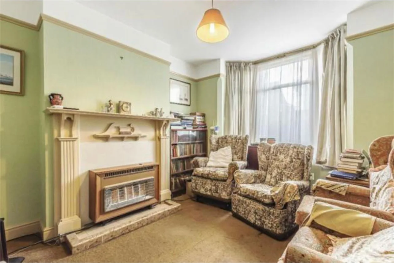 A front reception room before refurbishment, with a gas fire set into the fireplace and no radiator in the room