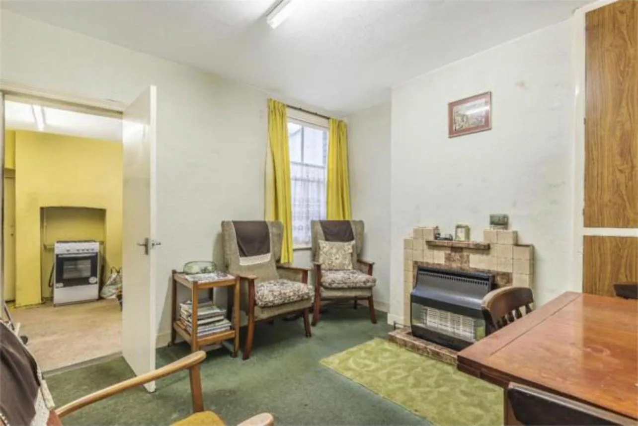The second reception room before refurbishment, heated by a gas fire set into a tiled fireplace