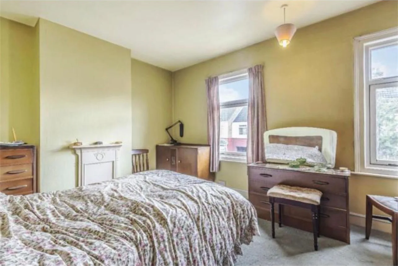 A bedroom before refurbishment, with dated decoration and no radiator on any wall
