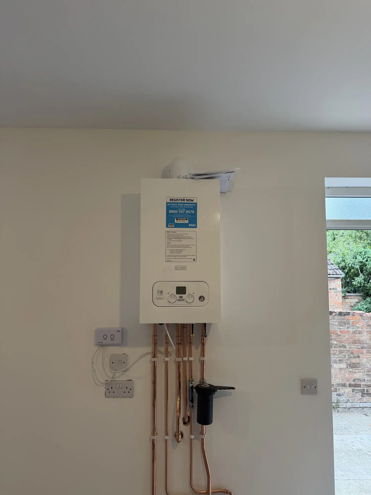 A newly installed combi boiler with tidy copper pipework and a magnetic system filter