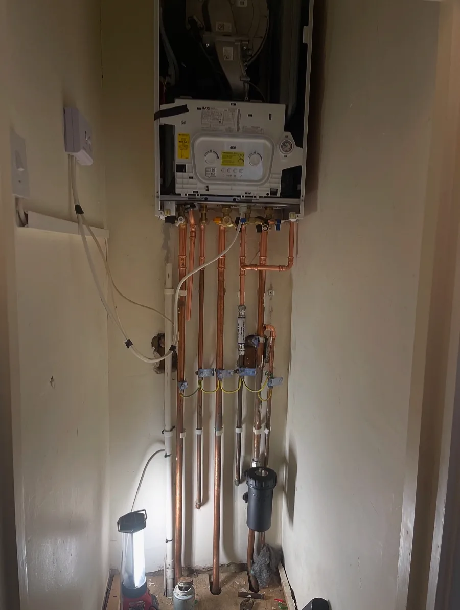A boiler installation in progress with the casing off and new copper pipework and isolation valves fitted below.