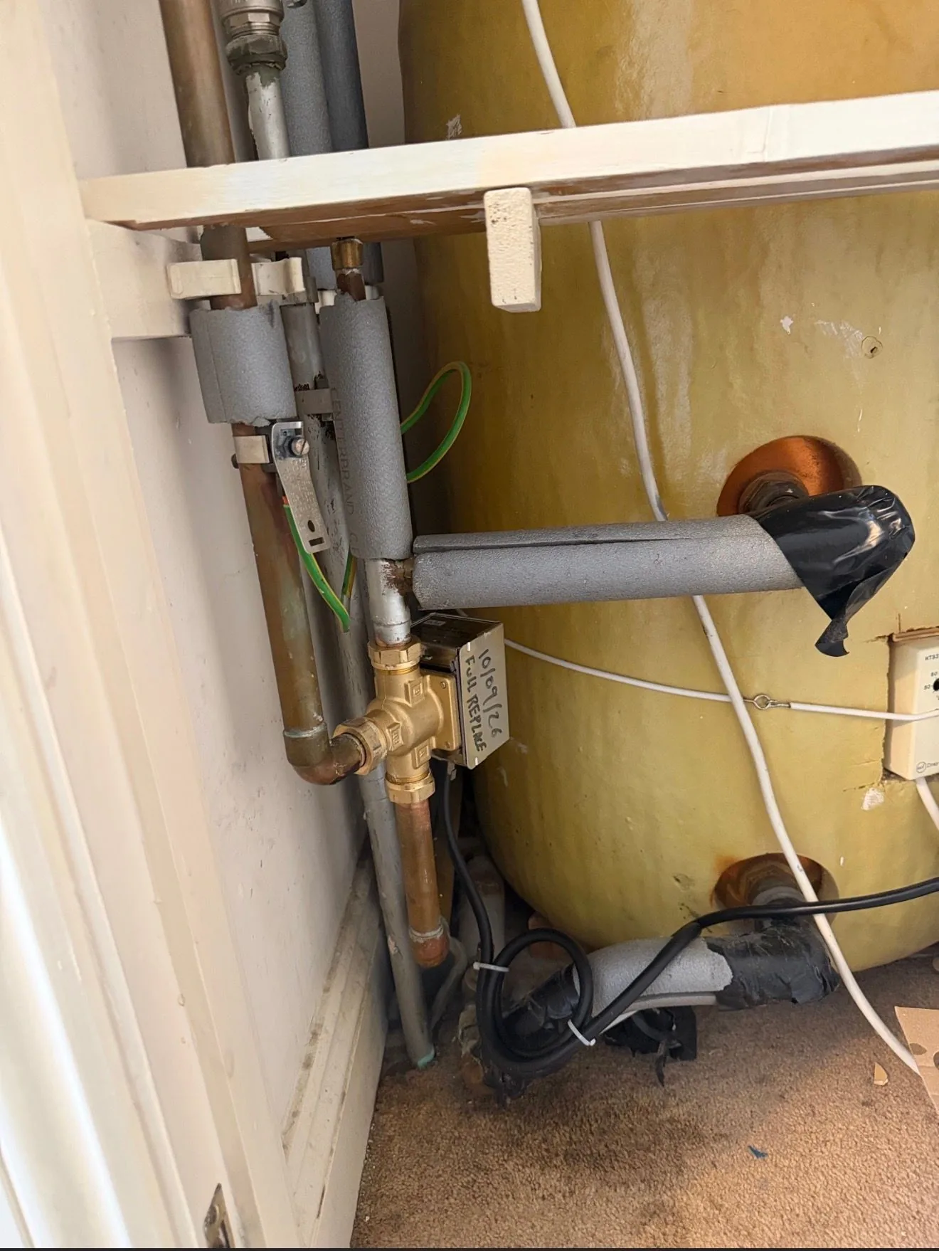 A motorised zone valve and pipework on a hot water cylinder during a central heating repair.