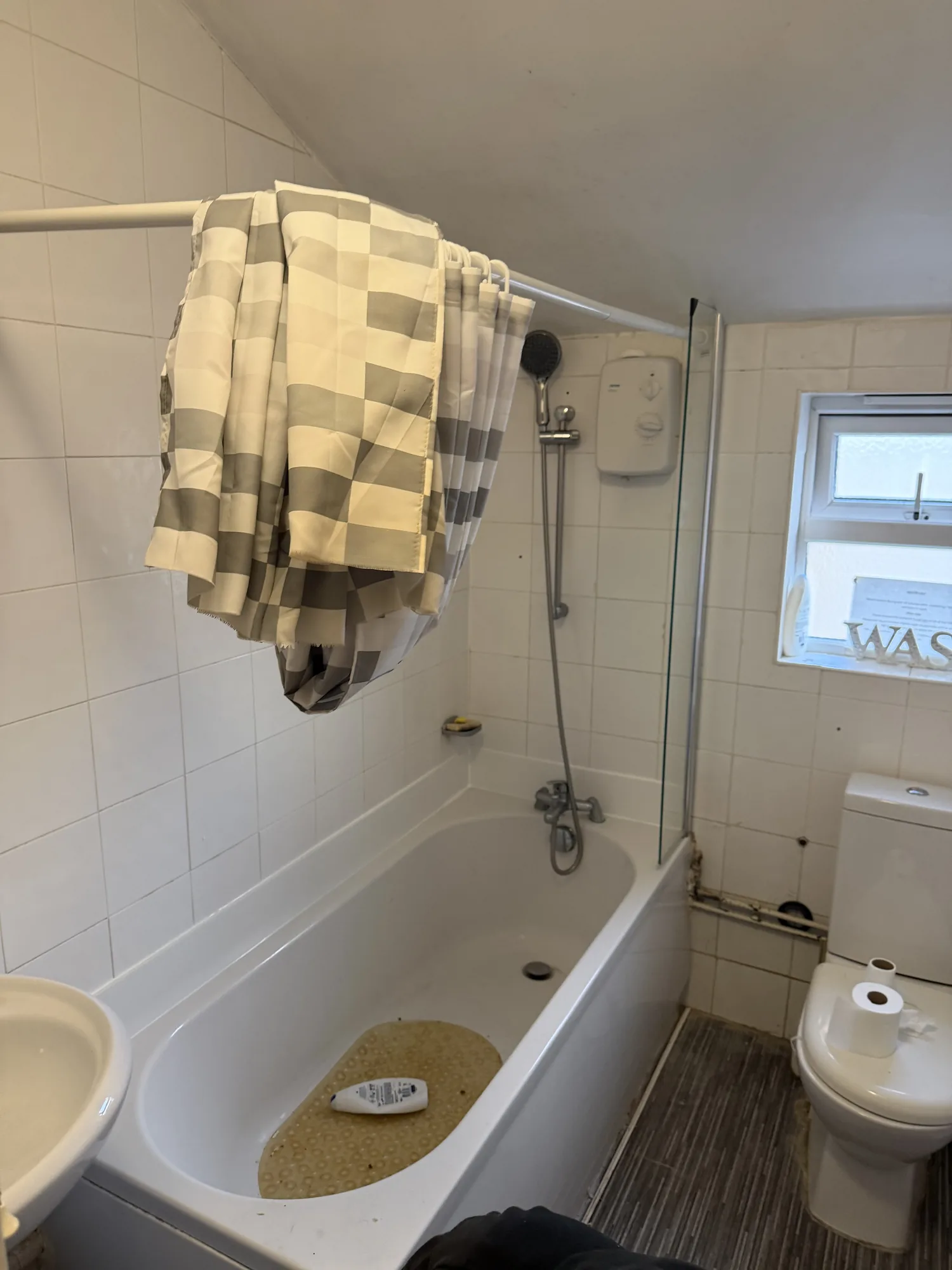 An existing family bathroom assessed on a repair visit, with an electric shower over the bath.