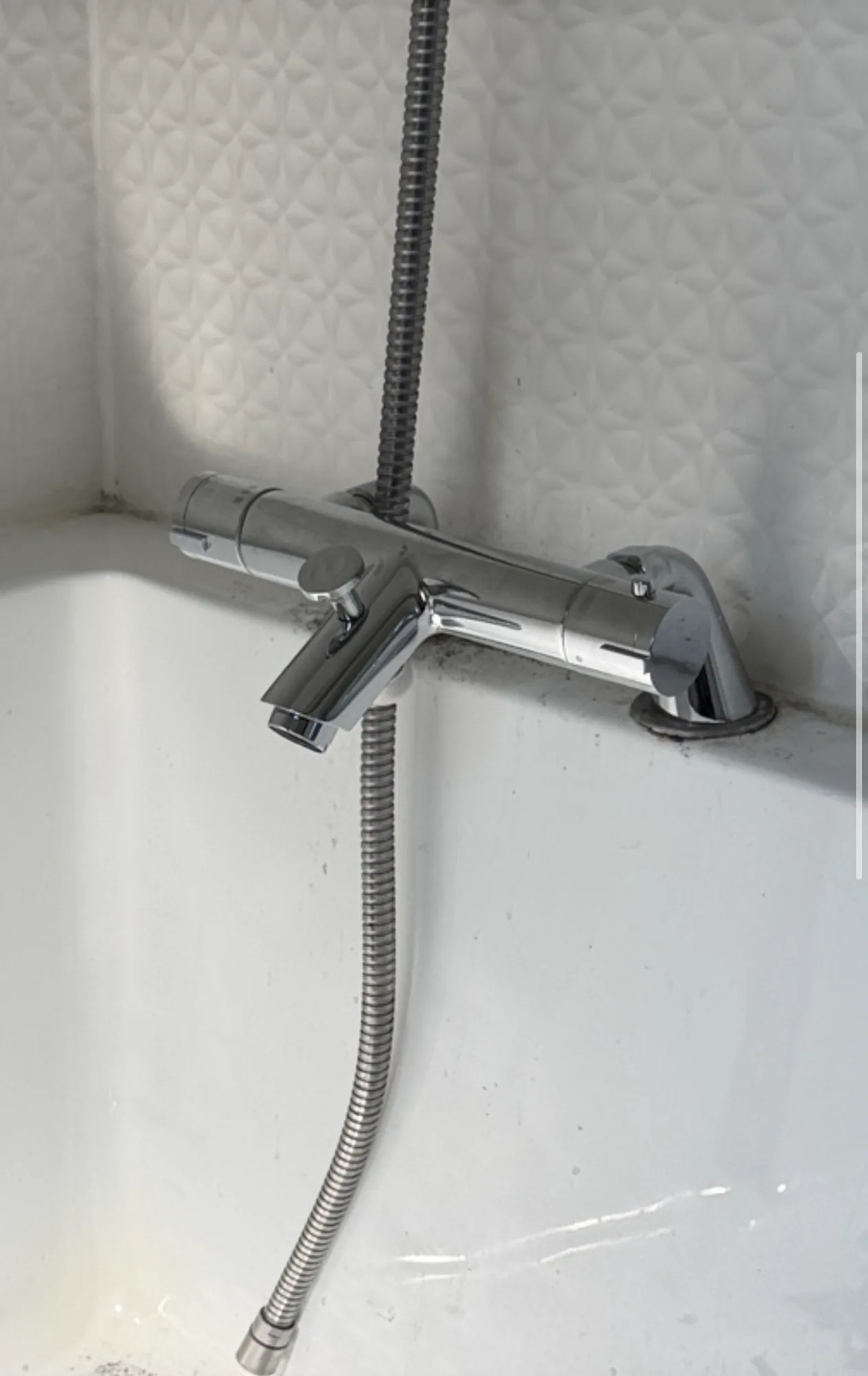 A chrome bath and shower mixer tap fitted to the rim of a white bath.