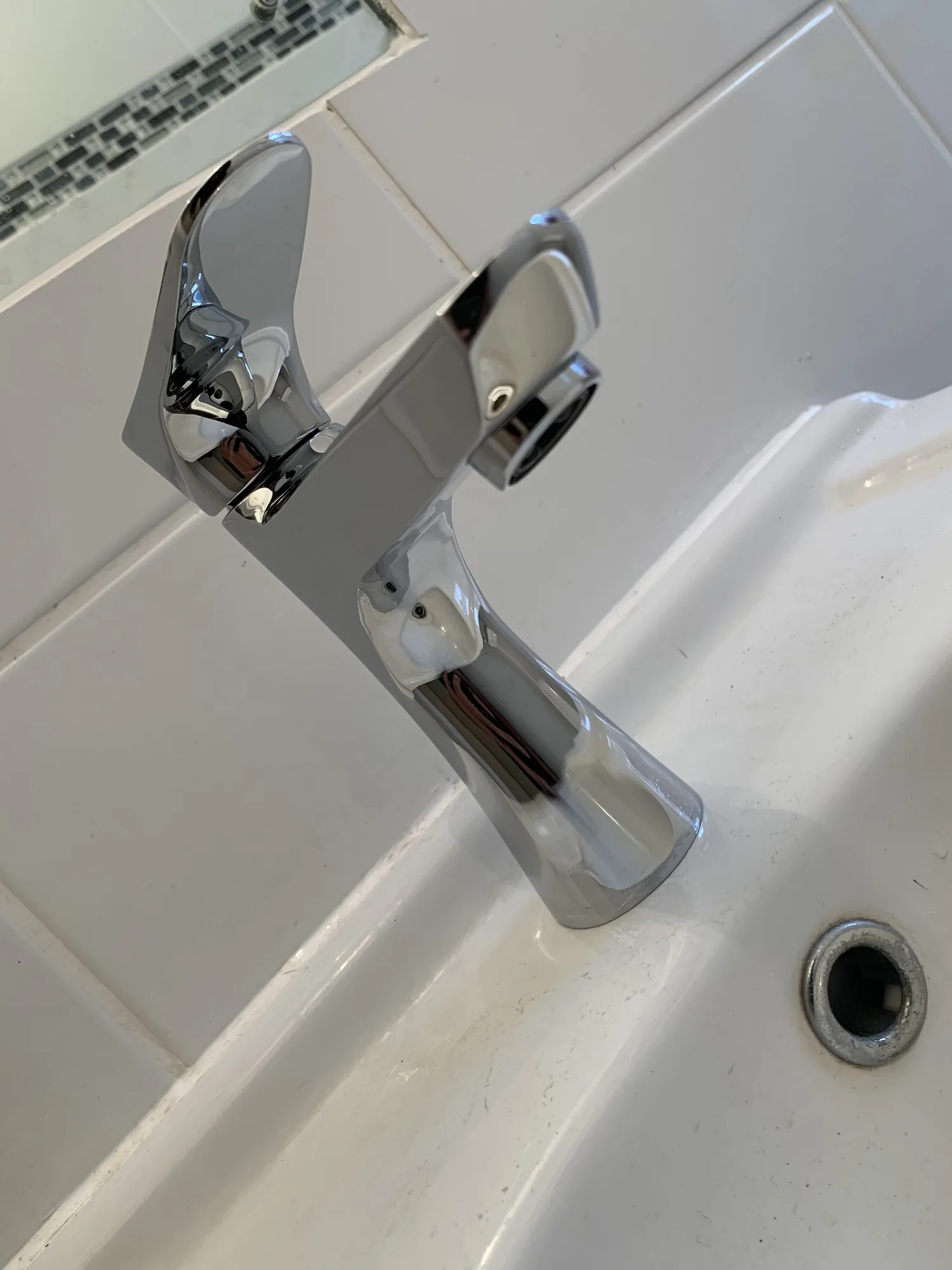 A chrome single lever basin mixer tap newly fitted on a white bathroom basin.